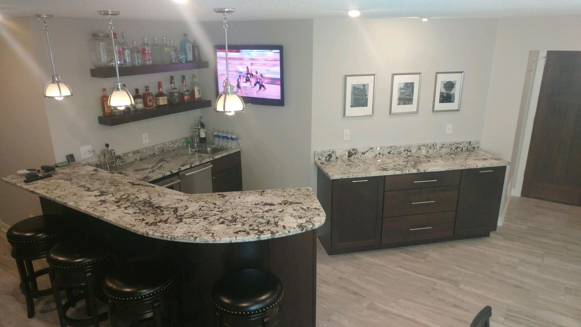 Espresso-colored home bar with a curved stone countertop and storage cabinets