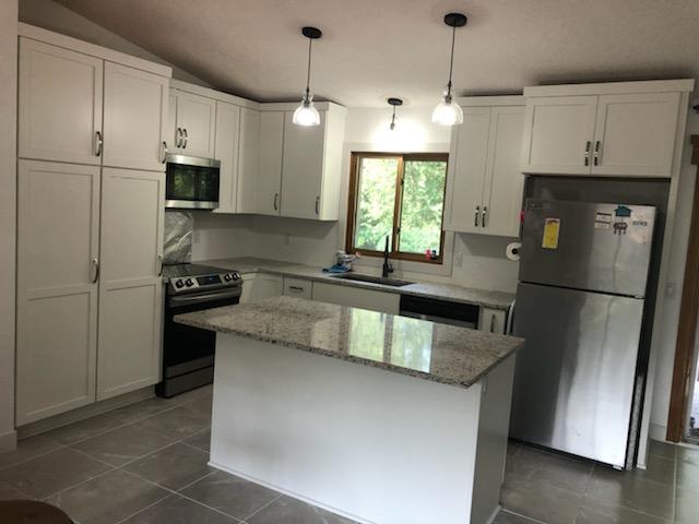White kitchen cabinets and matching island with stone countertop
